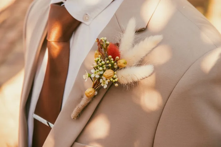 Close-up of a stylish wedding boutonniere on a tan suit jacket, perfect for grooms.