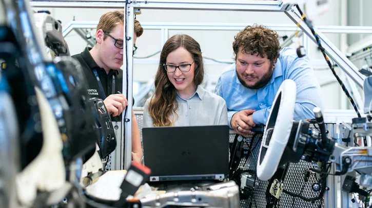 Engineers collaborating on a car project in a modern automotive workshop using advanced technology.