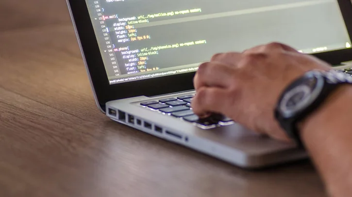 A close-up shot of a person coding on a laptop, focusing on the hands and screen.