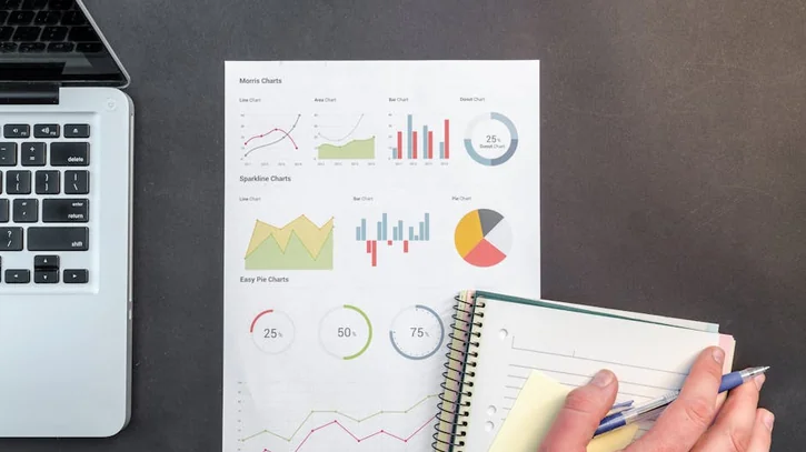 Overhead view of a business desk with charts and a laptop, ideal for data analysis concepts.
