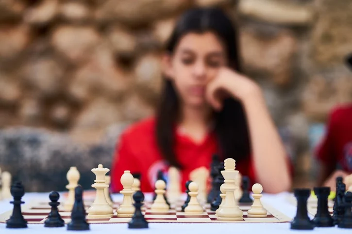 Child deeply focused on a strategic chess game outdoors in Turkey.