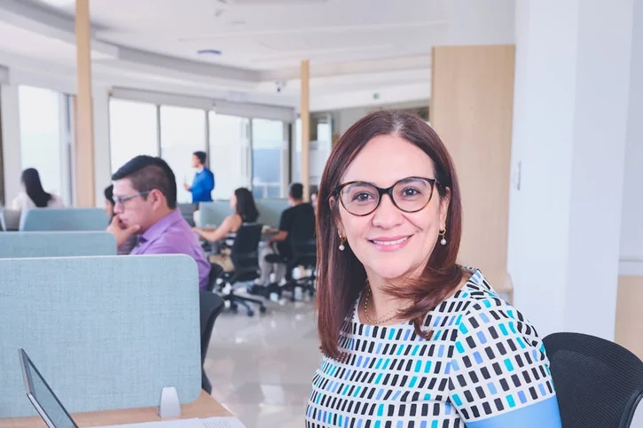 Confident woman in vibrant office, highlighting teamwork and productivity.