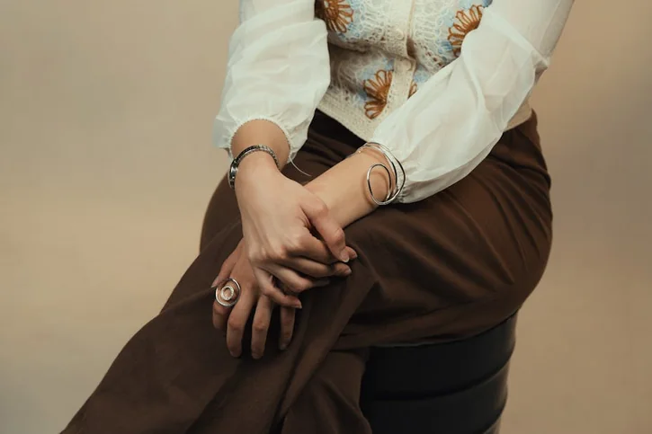 A stylish woman sits elegantly, showcasing jewelry and fashion.