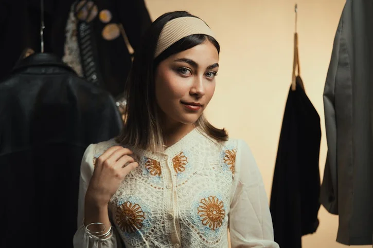 Elegant woman wearing vintage-style dress and headband indoors.
