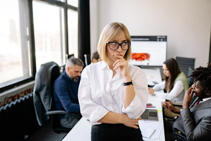 A focused businesswoman thinking during a team meeting in a modern office.
