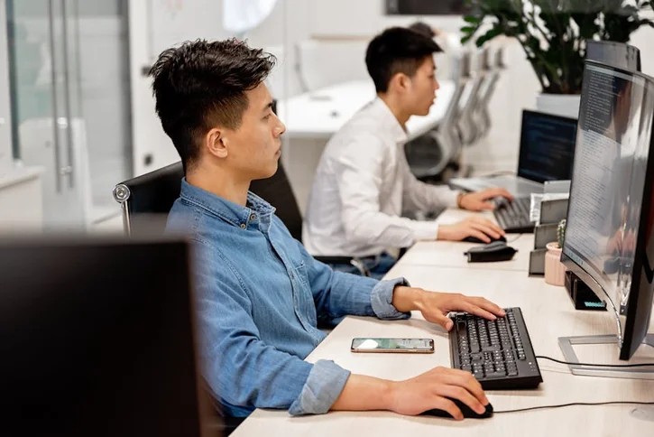 Young professionals working on computers in a modern office environment, focused on their tasks.