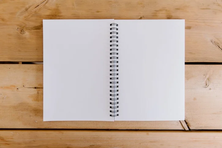 Top view of an open spiral notebook on a wooden desk, perfect for copyspace.
