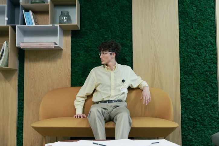 カジュアルなソファに座って座談会用の服装を整える男性エンジニア。