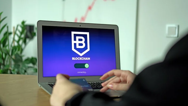 ブロックチェーン接続画面を表示するノートPCの近くでカードを持つ手