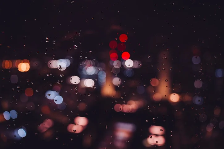 Bokeh city lights and raindrops on glass create a magical nighttime ambiance in London.