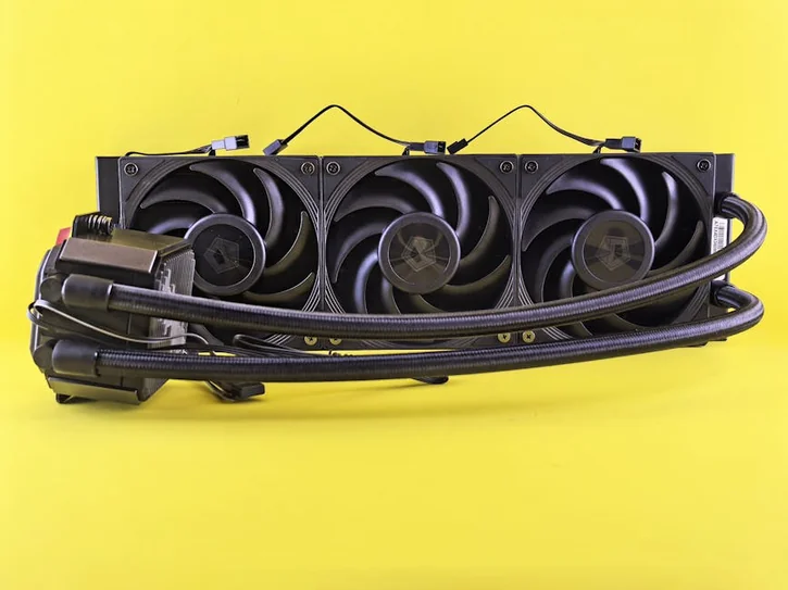 Close-up of a triple fan water cooling system against a bright yellow backdrop.