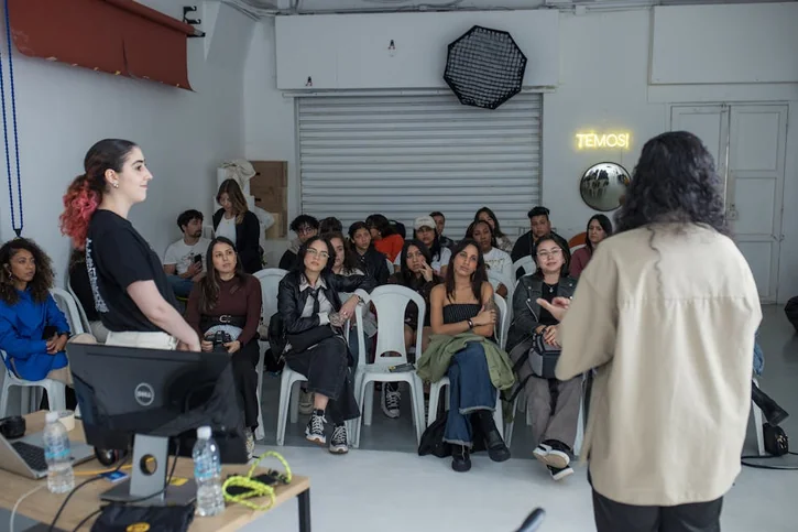 A diverse group of adults attentively listening to a speaker during an interactive workshop session indoors.
