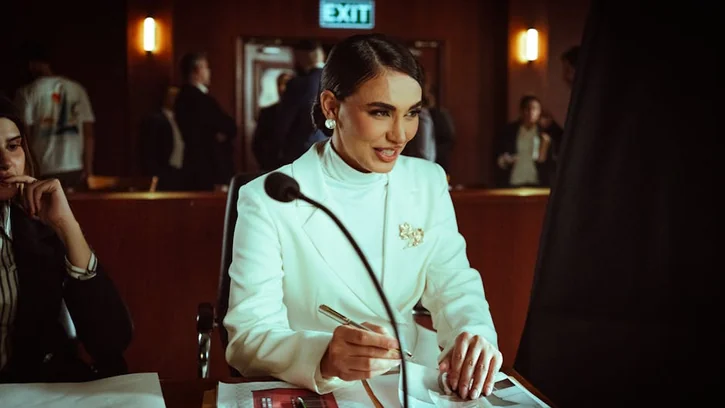 Confident woman in white suit conducting a business meeting in an office setting.
