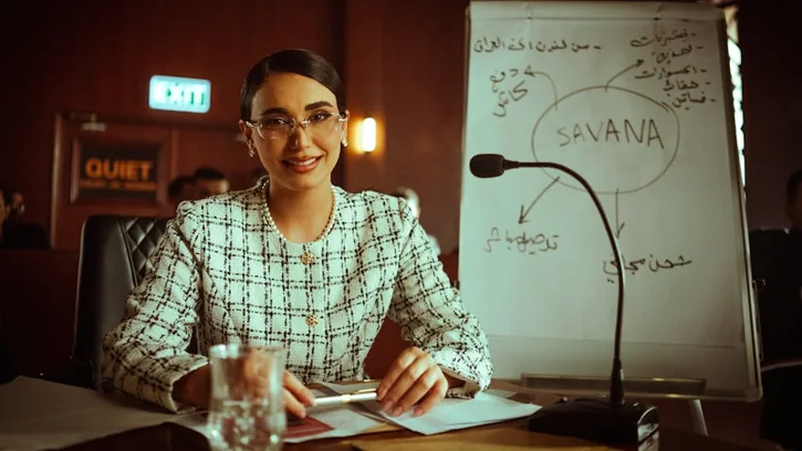 Businesswoman presents strategy on whiteboard in an office setting.