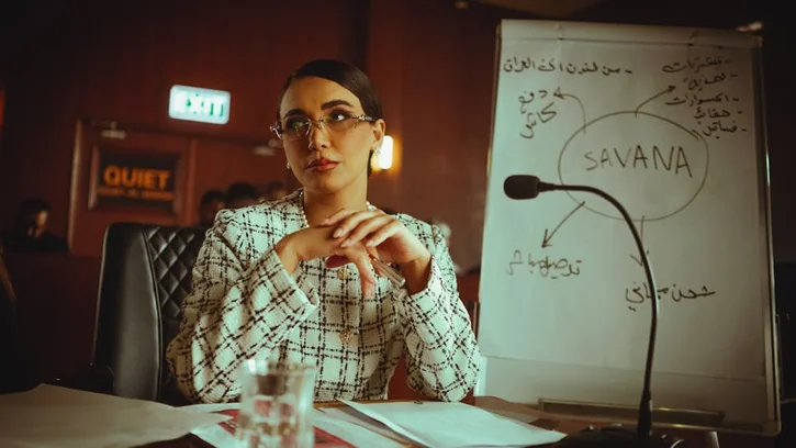 Middle Eastern woman in a conference room presenting ideas on a whiteboard.