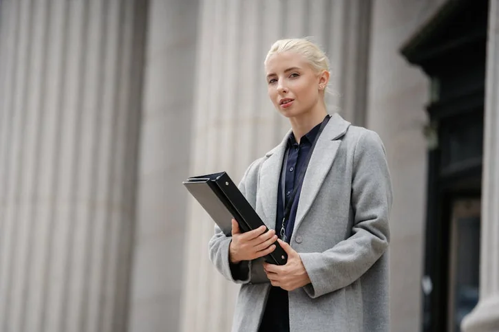 Portrait of a confident businesswoman holding documents in an urban setting with pillars.