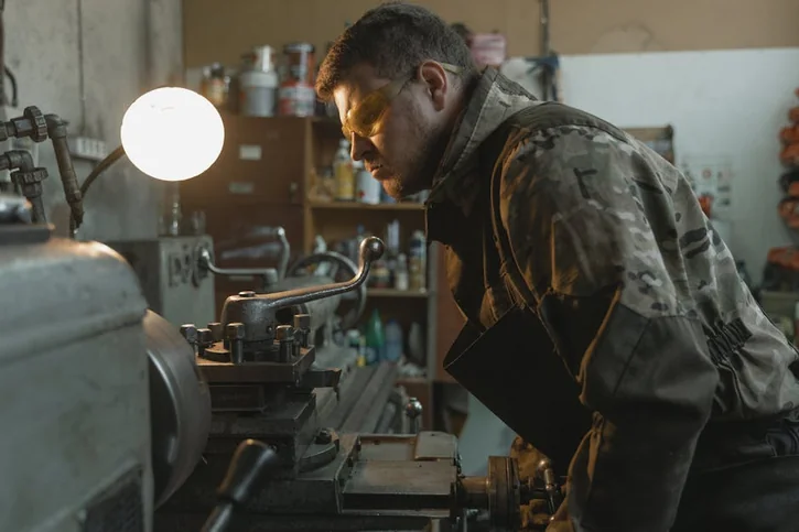Focused craftsman using a lathe machine in an industrial setting.