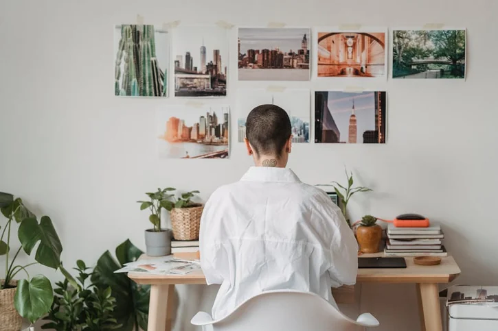 Woman working on a laptop in a stylish home office with art and plants.