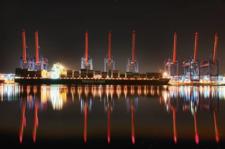 Stunning night view of a container ship docked at Hamburg port reflecting in water.