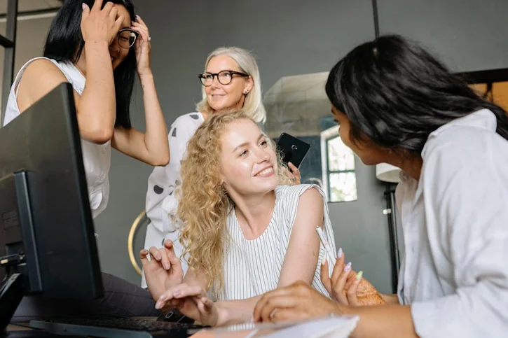 A dynamic group of diverse businesswomen collaborating in an office, sharing ideas and smiling.