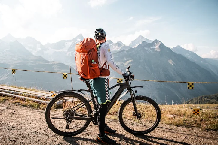 Cyclist with backpack enjoying a scenic mountain view in Saas-Fee, Switzerland.
