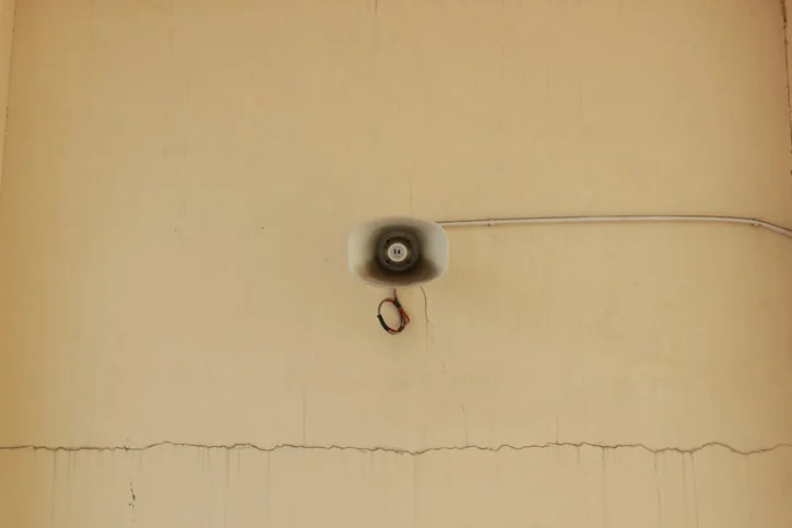 A mounted megaphone on a cracked wall highlights urban decay and communication themes.